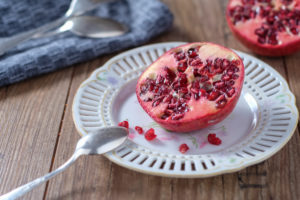 Half pomegranate on old porcelain plate Half pomegranate on old porcelain plate